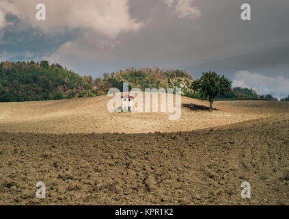 Little funny house in the middle of a plowed field. Loiano, Bologna, Italy. Stock Photo