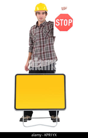 Young bricklayer holding stop sign Stock Photo