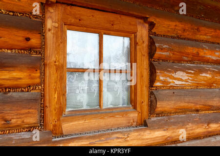 In the wall made of wooden logs, there is a small window in the wooden frame. This is an example of a typical architectural style for the Podhale regi Stock Photo