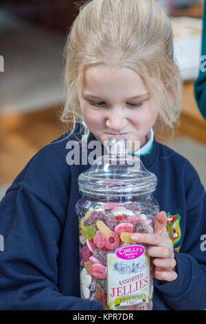 Child holding a large plastic jar of assorted jellies Stock Photo
