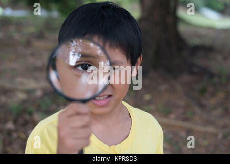 young asian boy looking through magnifying glass. education concept Stock Photo