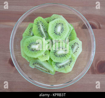 Bowl full with high in vitamins Kiwi fruit slices isolated on wooden background Stock Photo