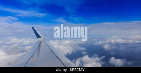 Fluffy white clouds on a blue sky from a plane window background. Space for text. Stock Photo