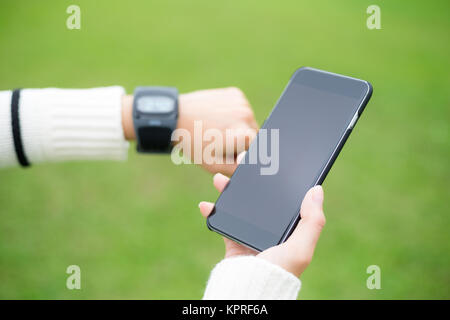 Woman with wearable watch and cellphone over green background Stock Photo