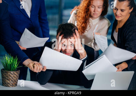 Stressed Business Man In Office surrounded by colleagues with documents in hands Stock Photo