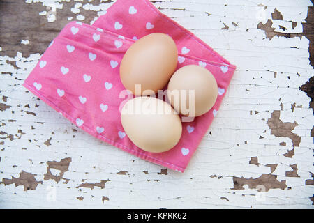 Eggs on tablecloth over wooden background Stock Photo