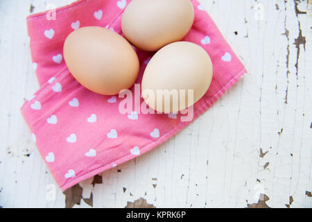 Eggs on tablecloth over wooden background Stock Photo
