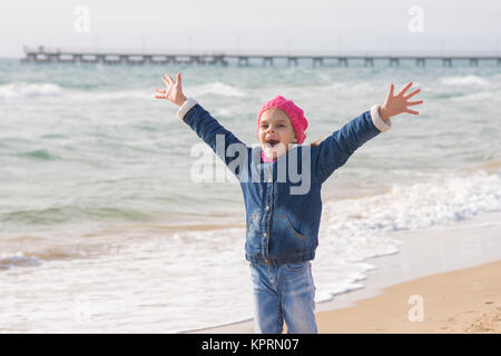 Seven-year girl rejoices arrival of the sea on the coast in the spring Stock Photo