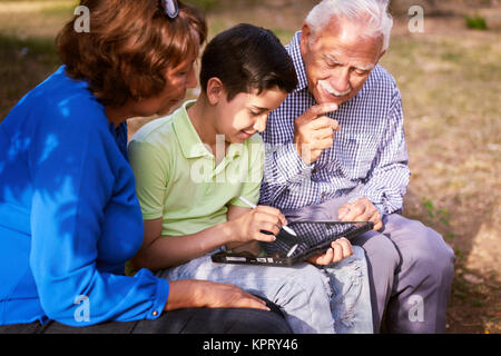 Grandparents And Grandson Studying Homework On Tablet PC Stock Photo