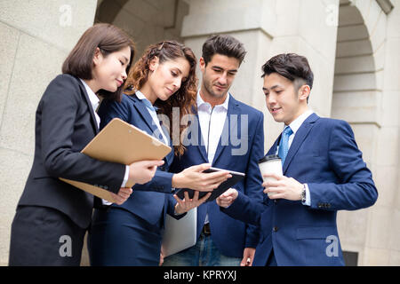 Group of business people discuss on tablet Stock Photo