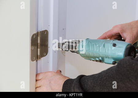 Worker using brad nail gun installs doors Carpenter using a nail gun Air gun for nailing using nail gun Stock Photo