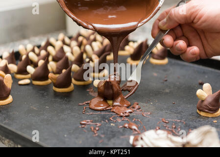 pastry chef covering the biscuits with melted chocolate Stock Photo