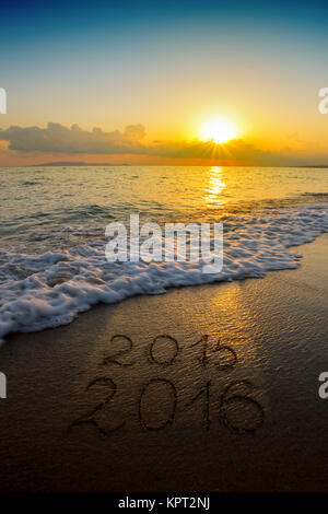 New Year 2016 is coming concept - inscription 2015 and 2016 on a beach sand, the wave is almost covering the digits 2015 Stock Photo