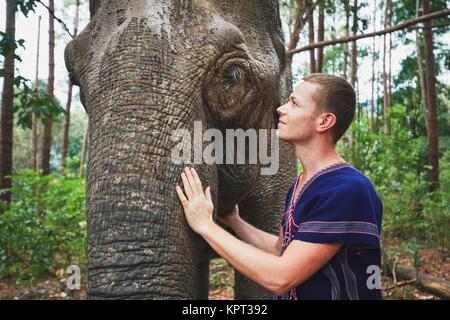 Face to face. Young traveler with friendly elephant in tropical rainforest in Chiang Mai Province, Thailand. Stock Photo