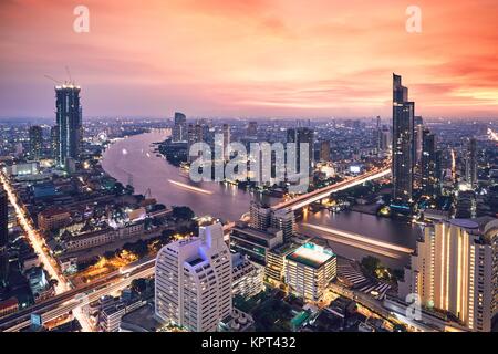 Bangkok during golden sunset. City skyline with traffic on the roads and Chao Phraya River.