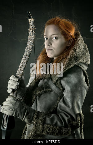 girl archer in a costume with bow isolated in a dark background Stock Photo