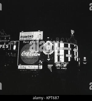 1960s, historical picture showing advertising signs and promotional slogans  lit up at night at Piccadilly Circus in London's West End, England, UK. Stock Photo