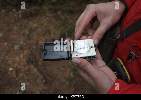 A man using a compass in a forest Stock Photo