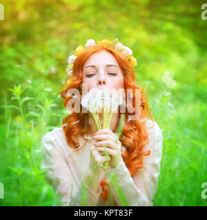 Beautiful female blowing on a dandelion flowers Stock Photo
