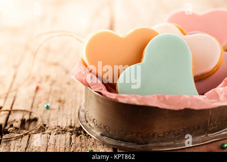 Festive heart shaped fondant cookies with colorful glazing on a rustic wooden table with copy space to celebrate Valentines Day, anniversary or wedding Stock Photo
