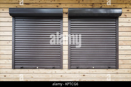 Wooden wall with two windows protected with roller shutters, background texture Stock Photo