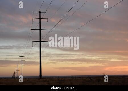 Long row of steel utility poles and high voltage electrical power lines fading into the distant horizon in the High Plains region of the USA Stock Photo