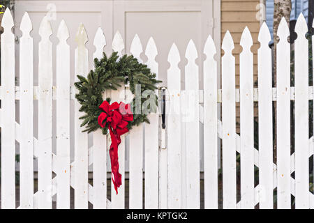 A wooden picket fence of a historic home decorated with a Christmas wreath on Water Street in Charleston, SC. Stock Photo