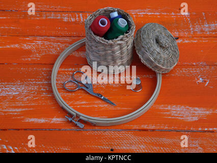 Spools of thread in a wicker basket and items for needlework Stock Photo