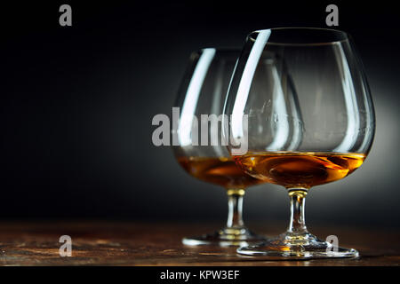 Classic background composed of two goblets filled with bourbon sitting on a wood table in a dark room Stock Photo