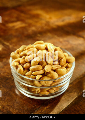 Glass bowl of roasted peanuts or groundnuts for nutritious snacks on a wooden table with copy space, high angle view Stock Photo