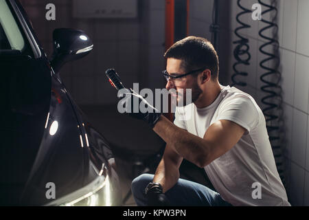 man checks polishing with a torch Stock Photo