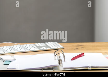 Open folder with keyboard and phone lying on wooden desk Stock Photo