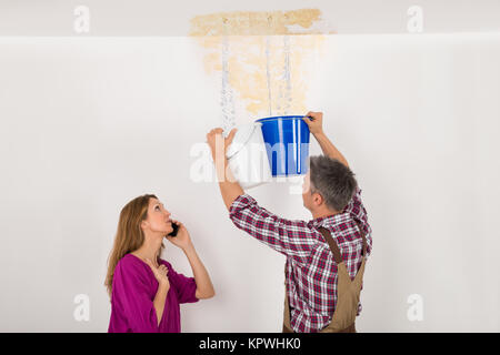 Worker Collecting Water In Bucket From Ceiling Stock Photo