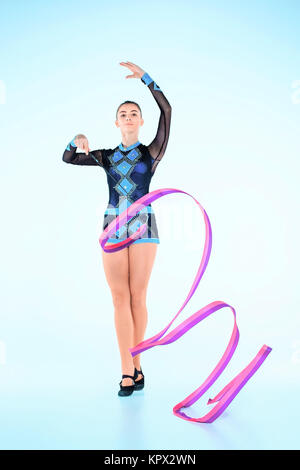 The girl doing gymnastics dance with colored ribbon on a blue background Stock Photo