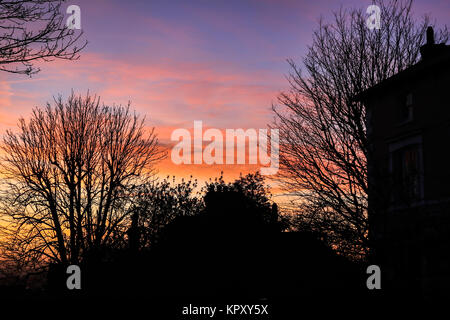 London, UK. 18th Dec, 2017. Residential rooftops are silhouetted against a stunning colourful sunrise with pink skies on a cold December morning in Wimbledon Credit: amer ghazzal/Alamy Live News Stock Photo