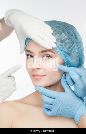 Plastic surgery concept. Doctor hands in gloves touching the beautiful woman face on white Stock Photo