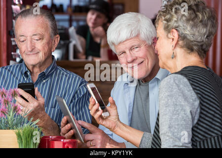 Happy  Trio in Coffee House Using Electronic Devices Stock Photo