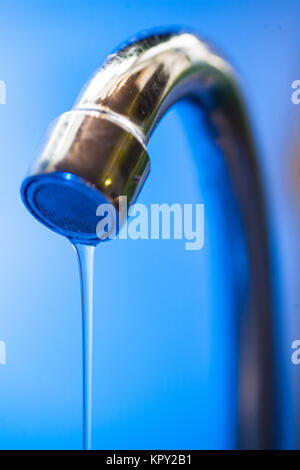 Water drips from the tap into a steel metal shell in blue tones close-up macro water runs out in the water supply shutdown liquid saving utility probl Stock Photo