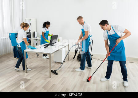 Group Of Janitors Cleaning The Office Stock Photo