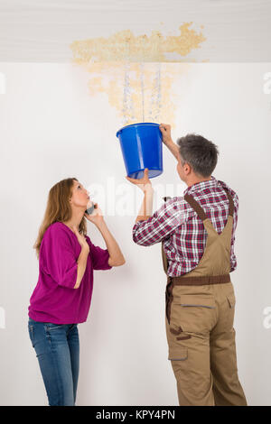 Worker Collecting Water In Bucket From Ceiling Stock Photo