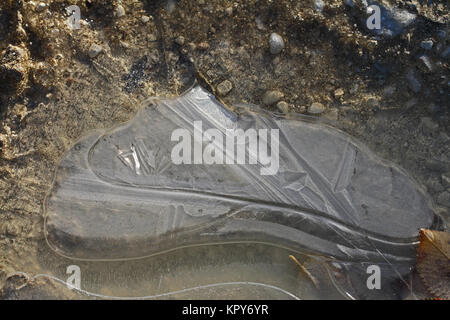 macro of an icy puddle or ice on a gravel driveway in winter in Italy Stock Photo