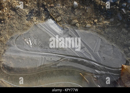macro of an icy puddle or ice on a gravel driveway in winter in Italy Stock Photo