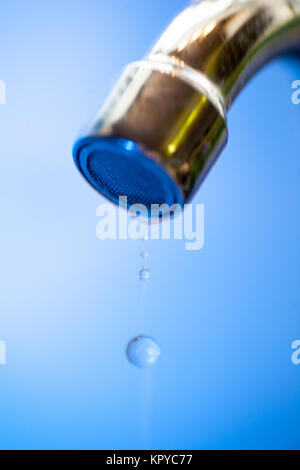 Water drips from the tap into a steel metal shell in blue tones close-up macro water runs out in the water supply shutdown liquid saving utility probl Stock Photo