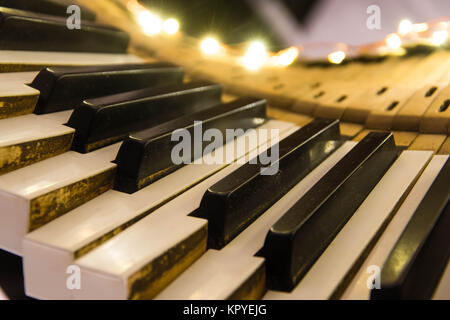 Old piano keyboard twisted with keys pushed down. Keys removed from the body of musical instrument lit up as a Christmas decoration Stock Photo