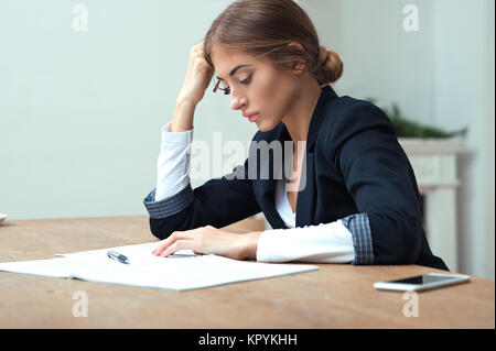 Pretty business lady working with data documents sitting at the table in office Stock Photo