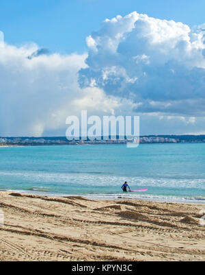 PLAYA DE PALMA, MALLORCA, SPAIN - DECEMBER 16, 2017: Surfer with pink board on winter beach on a windy day on December 16, 2017 in Mallorca, Balearic  Stock Photo