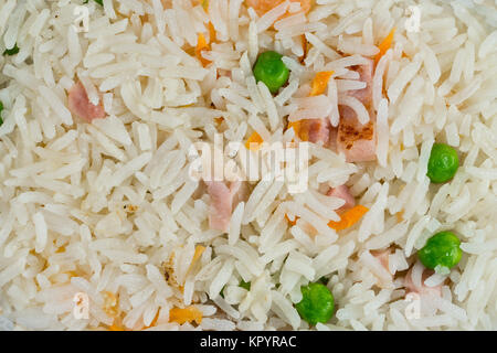 Meal background. Oriental rice dish with mixed meat, boiled egg, fresh vegetables like peas and carrot. Traditional Thai Food. Stock Photo