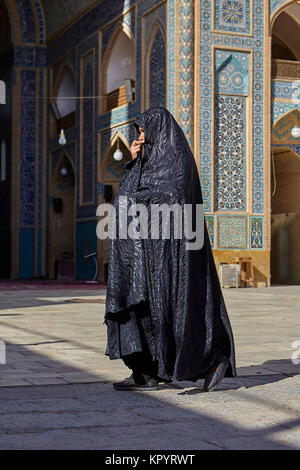 Yazd, Iran - April 21, 2017: An elderly woman in black Islamic clothes strolls around the mosque. Stock Photo