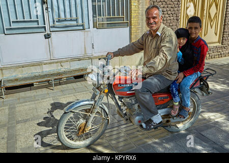 Yazd, Iran - April 21, 2017:  Mature Iranian man rides a motorcycle with his children, boy and girl in hijab. Stock Photo