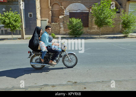 Yazd, Iran - April 21, 2017: A family of three Iranians is riding a motorbike on a city street. Stock Photo